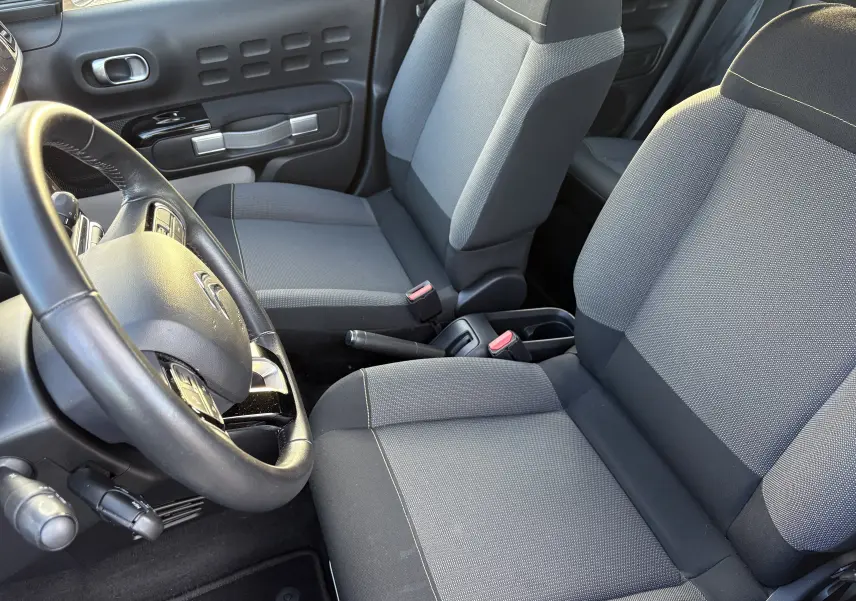 Vue intérieure côté conducteur de la Citroën C3 2018, sièges gris et volant avec commandes intégrées.