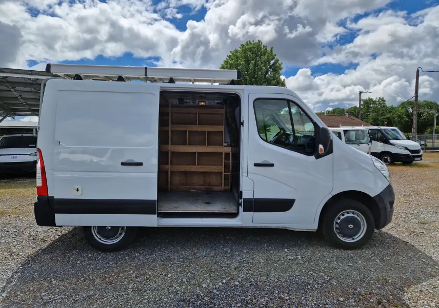 Vue de profil droit d’un Renault Master blanc 2019 avec porte latérale ouverte révélant un aménagement intérieur en bois.