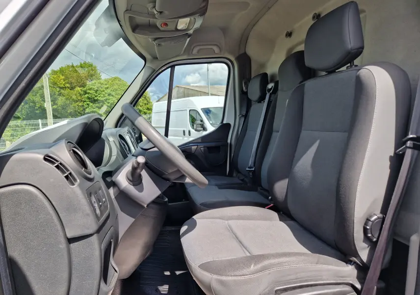 Vue intérieure côté conducteur du Renault Master blanc 2019, montrant les sièges 3 places et le tableau de bord simple.