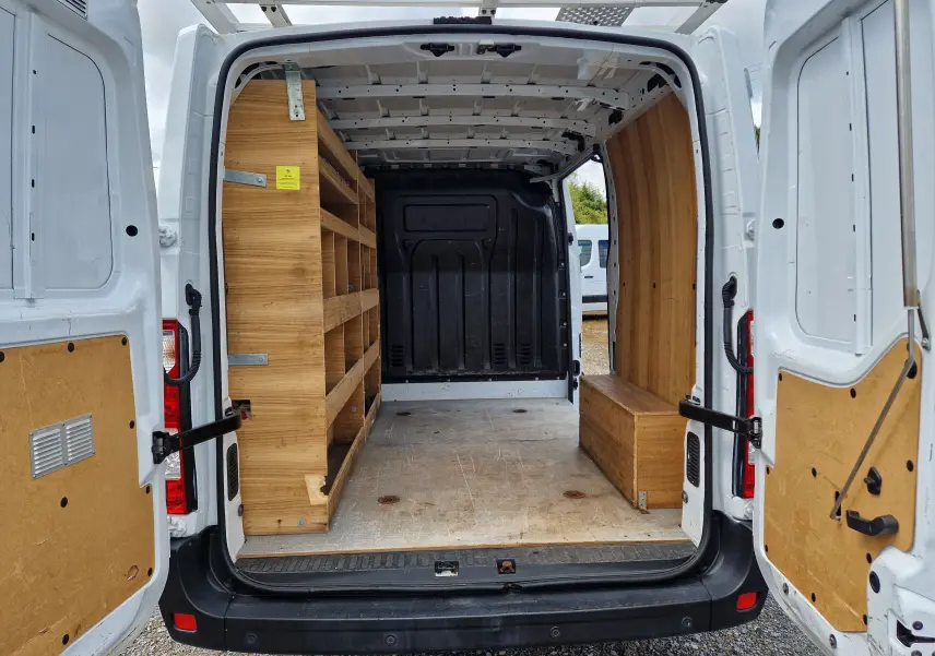 Vue arrière ouverte du Renault Master blanc 2019 avec aménagements bois intérieurs et étagères dans l’espace de chargement.