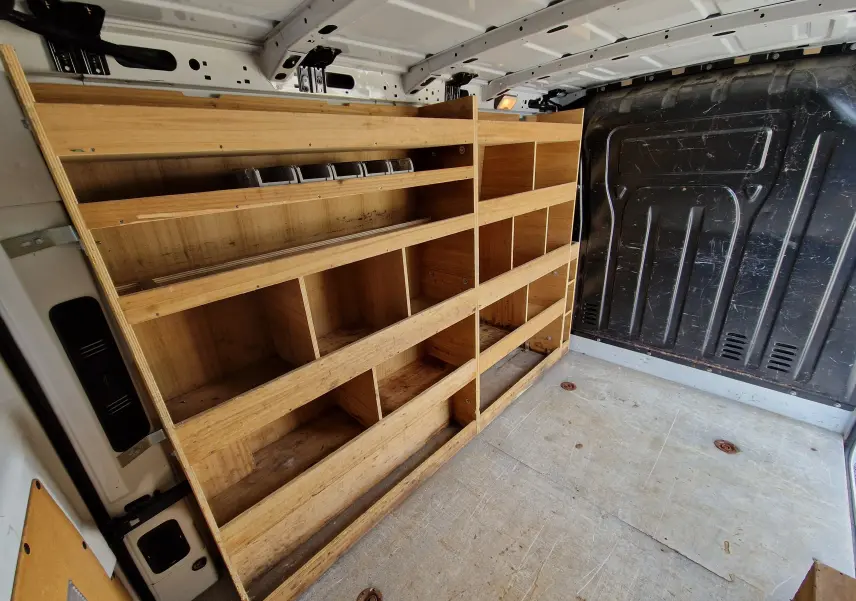 Vue intérieure arrière droite du Renault Master blanc 2019 avec aménagement bois de rangement et cloison noire.