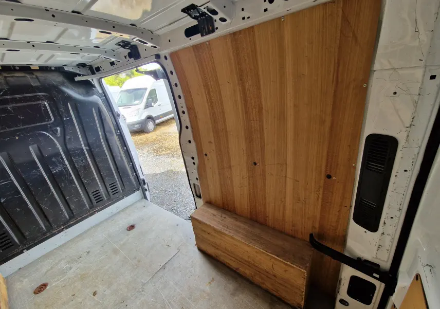 Vue intérieure arrière du Renault Master blanc 2019 avec habillage bois sur la cloison et plancher usé visible.