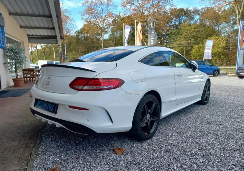 Mercedes Classe C Coupé blanc vue 3/4 arrière droit, avec jantes noires et toit ouvrant électrique visible.