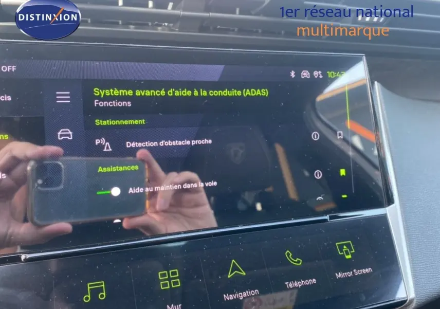 Vue rapprochée de l’écran tactile intérieur du Peugeot 308 Hybrid blanc, affichant les aides à la conduite avancées.