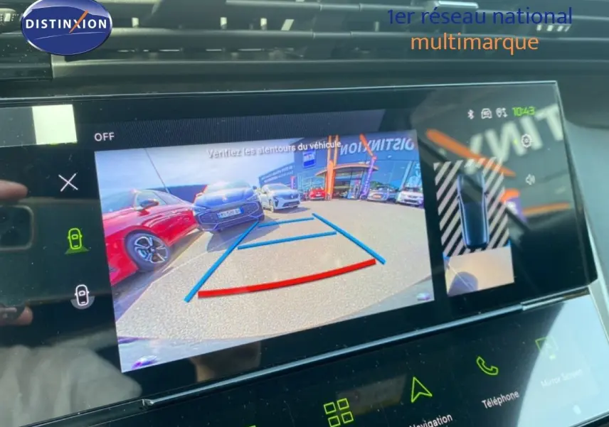 Écran multimédia montrant la caméra de recul d'une Peugeot 308 blanche, vue arrière avec lignes de guidage colorées.