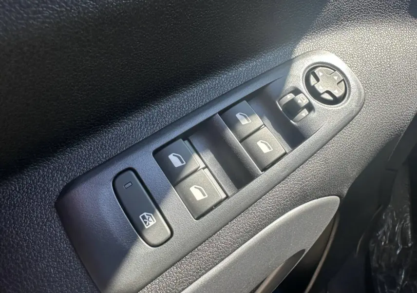 Gros plan sur les commandes des vitres électriques et réglage des rétroviseurs côté conducteur du Citroën Berlingo Sirkka Green.