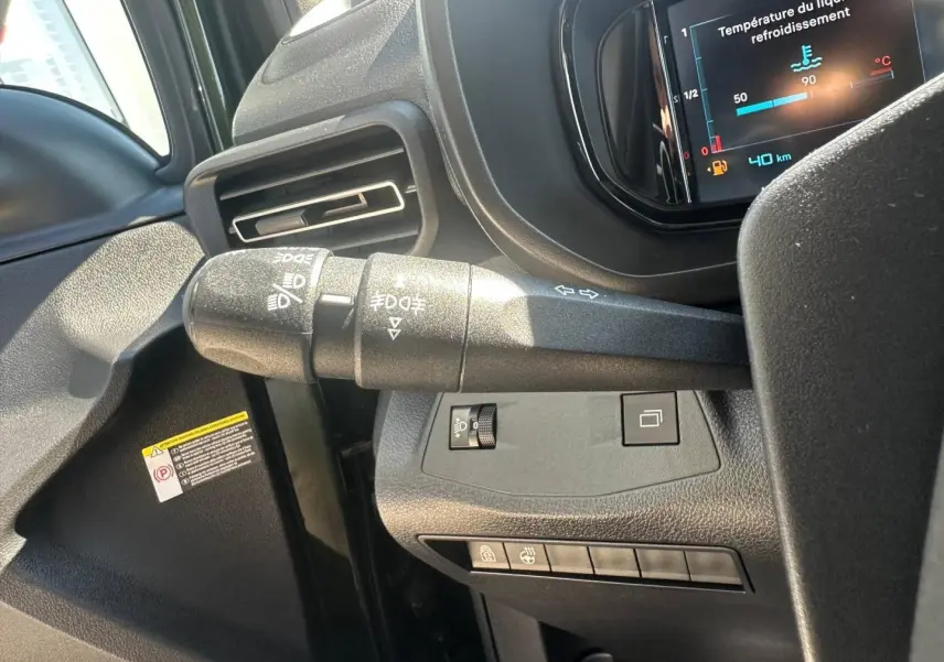 Gros plan sur la commande des feux à gauche du volant dans l’habitacle sombre du Citroën Berlingo 2026.