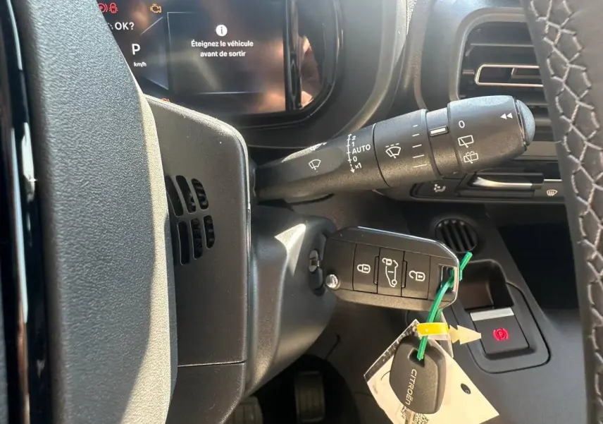 Vue rapprochée du tableau de bord et clé de contact du Citroën Berlingo 2026, avec affichage digital et volant partiel.