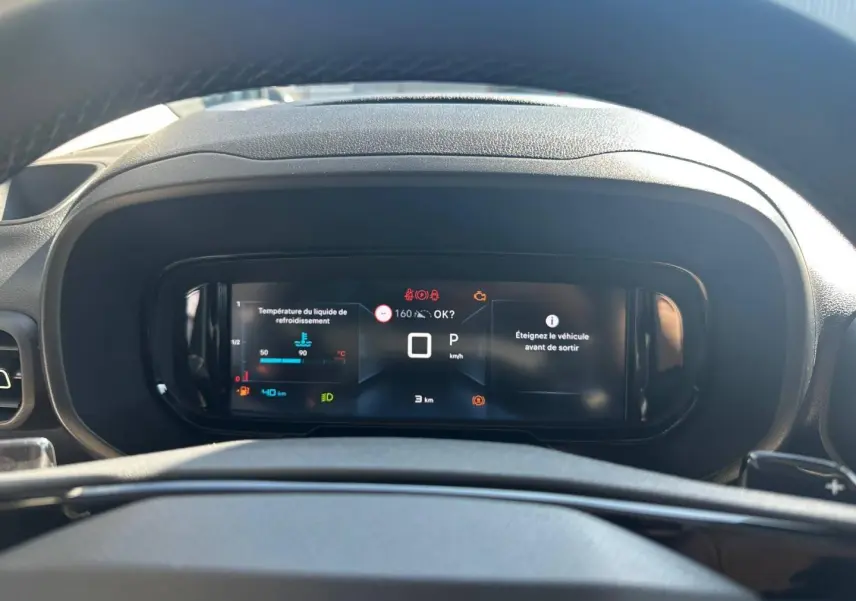 Vue rapprochée du tableau de bord numérique du Citroën Berlingo 2026, affichage des alertes et vitesse à zéro.