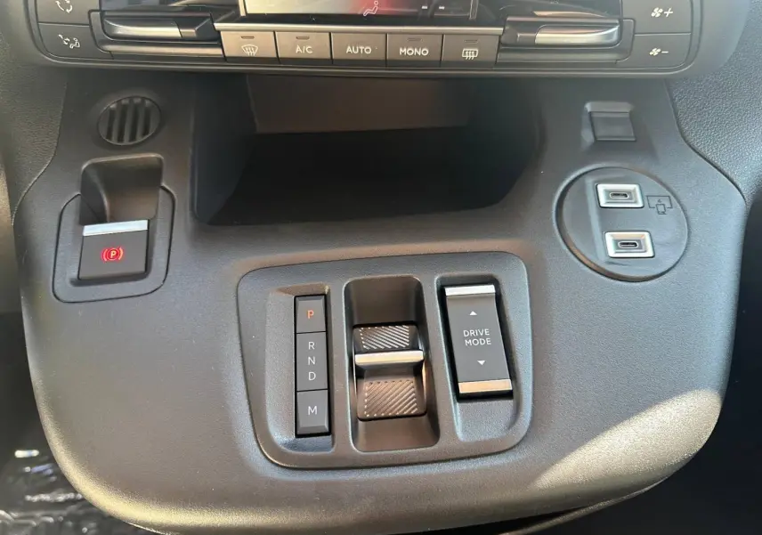 Vue rapprochée de la console centrale noire du Citroën Berlingo 2026 avec commandes boîte auto et climatisation.