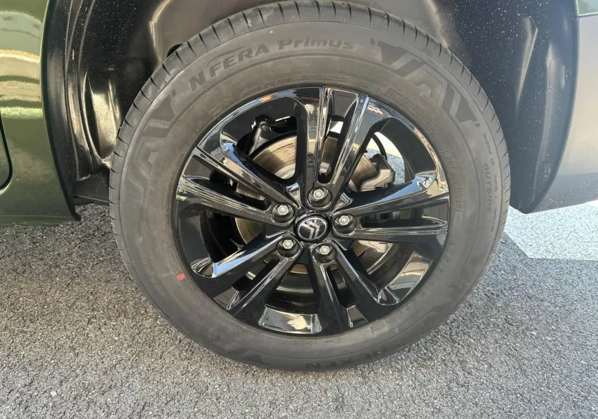 Gros plan sur la roue avant gauche du Citroën Berlingo Sirkka Green avec jante alu noire brillante.