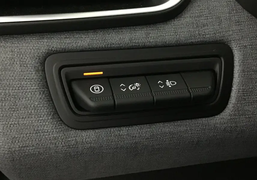 Panneau de commandes intérieures en tissu gris schiste de la Renault Clio V 2025, avec bouton de verrouillage éclairé en orange.