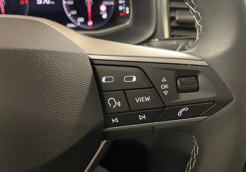 Gros plan sur les commandes du volant du SEAT Ateca 2024, finition Copa, avec cuir noir et coutures apparentes.