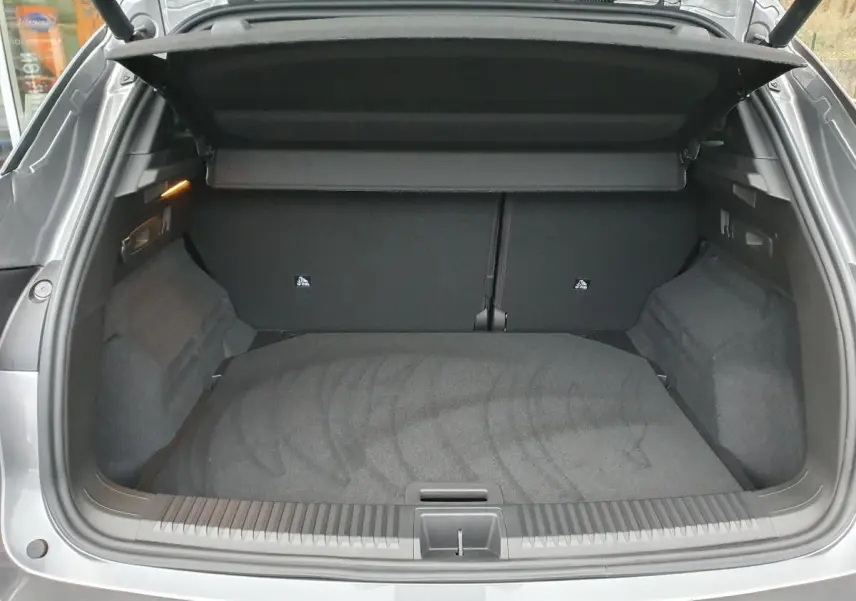 Coffre ouvert vu de l'arrière d'un Renault Austral gris schiste avec intérieur noir et cache-bagages déployé.