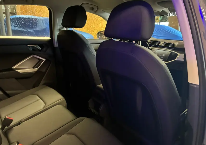 Vue intérieure arrière côté gauche de l'Audi Q3 Sportback 2021, sièges en cuir noir et tableau de bord visible.