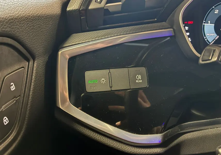 Gros plan sur les commandes d’éclairage à gauche du tableau de bord noir de l’Audi Q3 Sportback gris 2021.