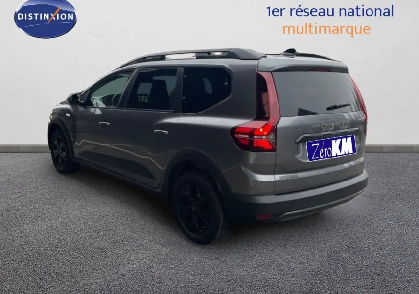 Vue 3/4 arrière droite d'un Dacia Jogger gris schiste métallisé avec feux arrière allumés et jantes noires.