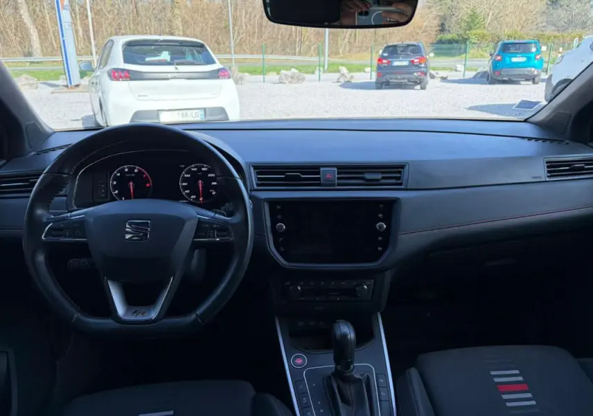 Vue intérieure frontale du tableau de bord et volant noir du SEAT Arona 2020, version FR avec détails rouges sur les sièges.