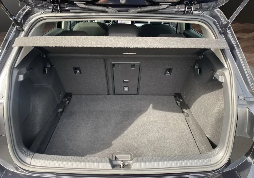Coffre ouvert d'une Volkswagen Golf VIII noire vue de l'arrière, montrant un espace de chargement propre et spacieux.