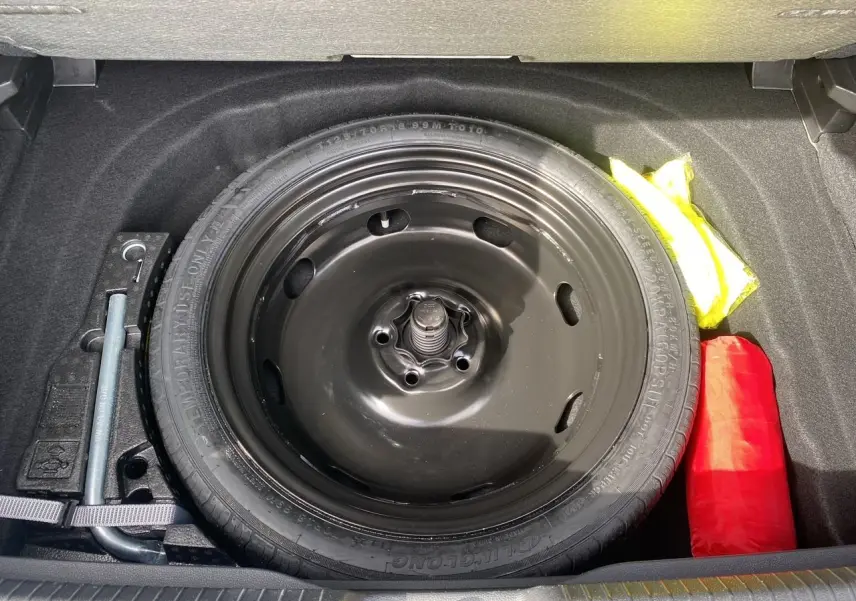 Roue de secours noire dans le coffre d'une Volkswagen Golf VIII 2022, avec outils et trousse de secours visibles.