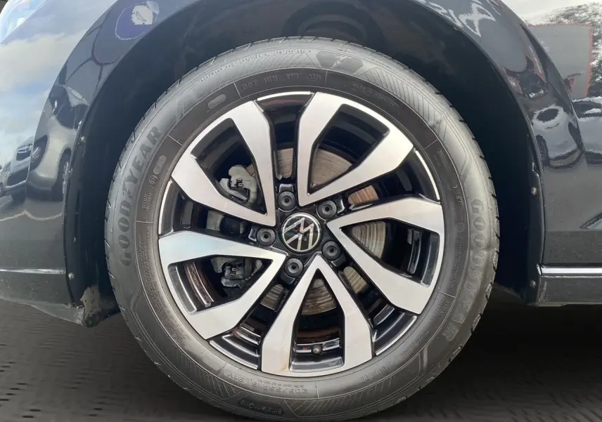 Gros plan sur la roue avant droite noire d'une Volkswagen Golf VIII 2022 avec jante alliage bicolore et pneu Goodyear.