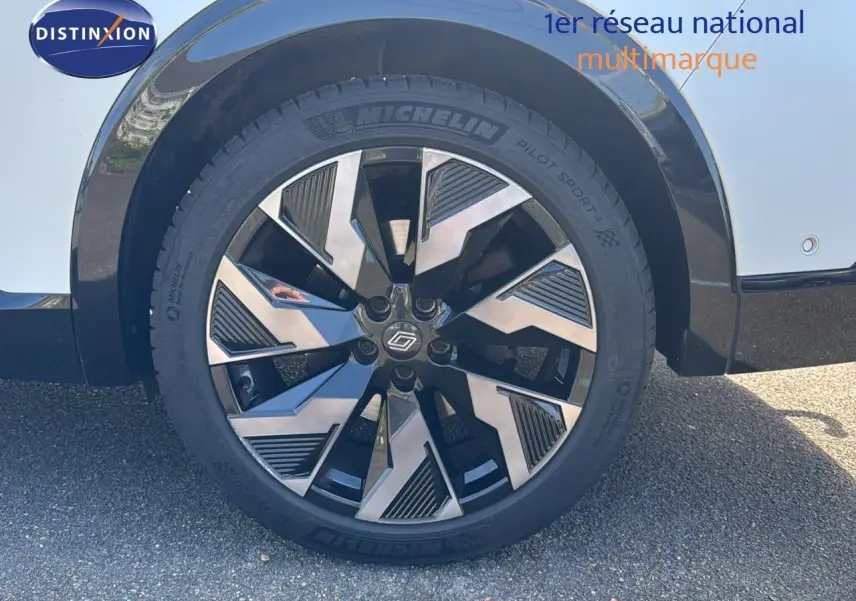 Gros plan sur la roue avant droite du Renault Rafale 2024 blanc satin avec jante alliage noire et argentée.