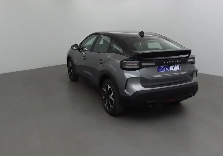 Vue 3/4 arrière droite d'une Citroën C4 2025 gris Mercury et noir avec toit noir et jantes 18 pouces.