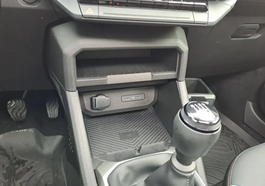 Vue rapprochée de la console centrale intérieure noire du Dacia Bigster 2025, avec levier de vitesse manuel et ports USB visibles.