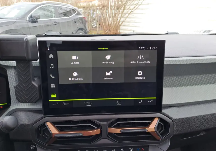 Vue intérieure centrée sur l'écran tactile du tableau de bord du Dacia Bigster 2025, avec aérateurs noirs et bronze.