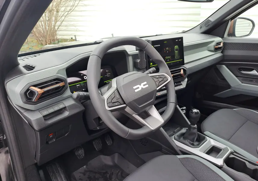 Vue intérieure côté conducteur du Dacia Bigster 2025 noir nacré, avec tableau de bord moderne et boîte manuelle.