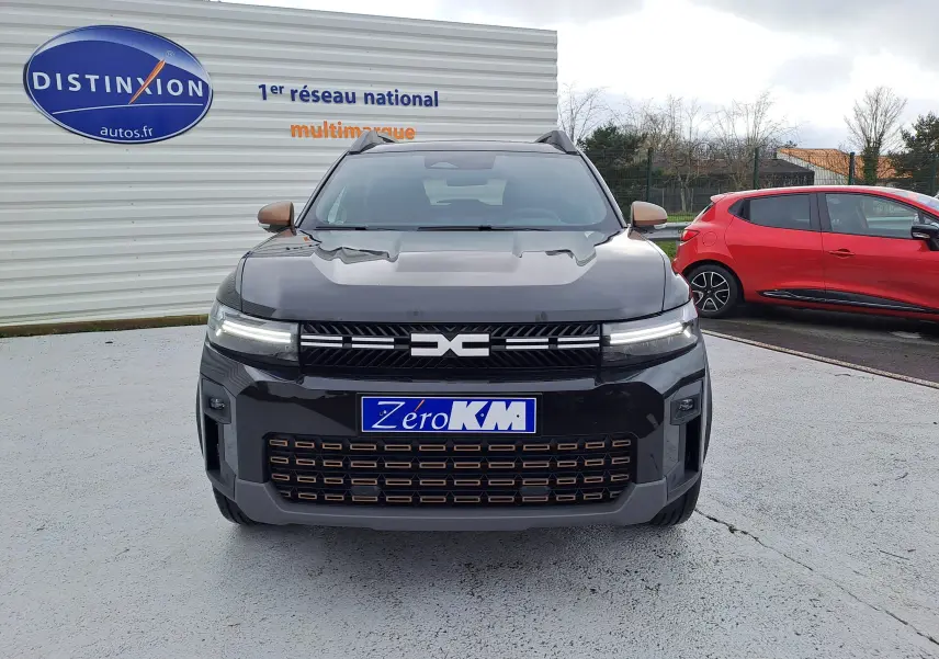 Vue avant du Dacia Bigster noir nacré avec calandre distinctive et feux LED allumés sur parking.