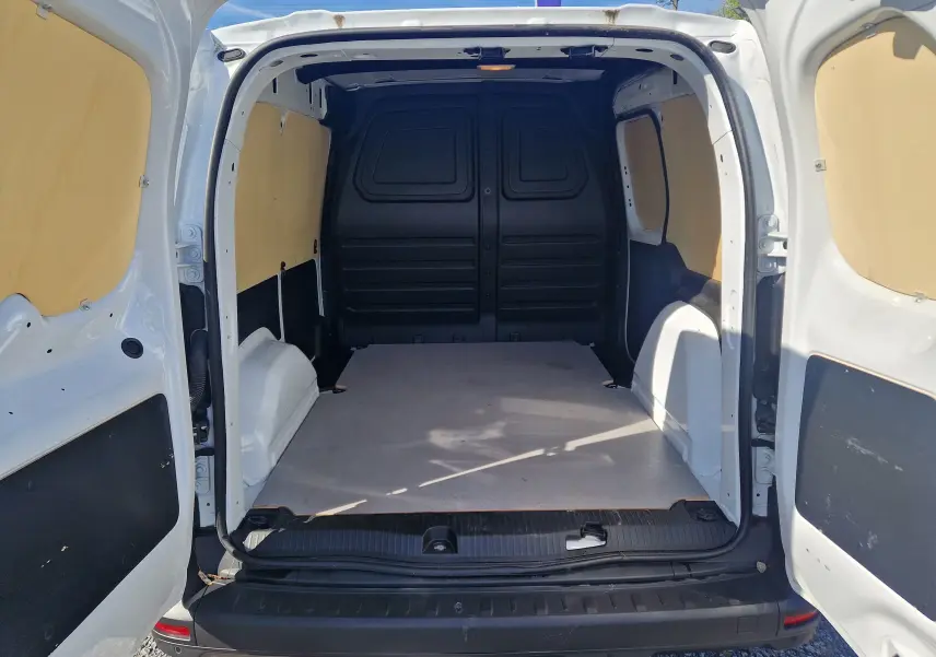 Vue arrière du Renault Kangoo blanc 2023, version 1.5 Blue dCi, montrant l’espace de chargement vide avec habillage bois.
