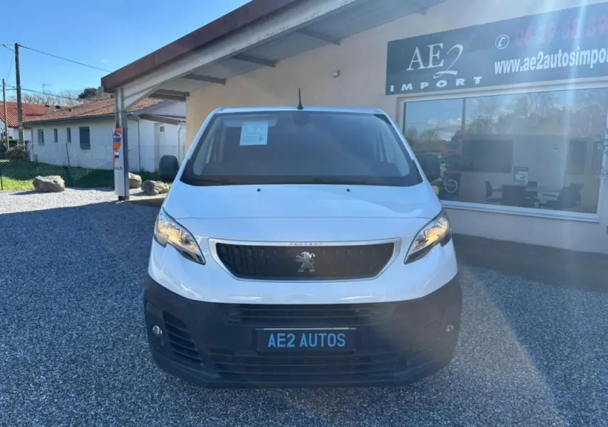 Vue avant d’un Peugeot Expert Fourgon blanc 2018 avec calandre noire et plaque AE2 AUTOS sur parking gravillonné.