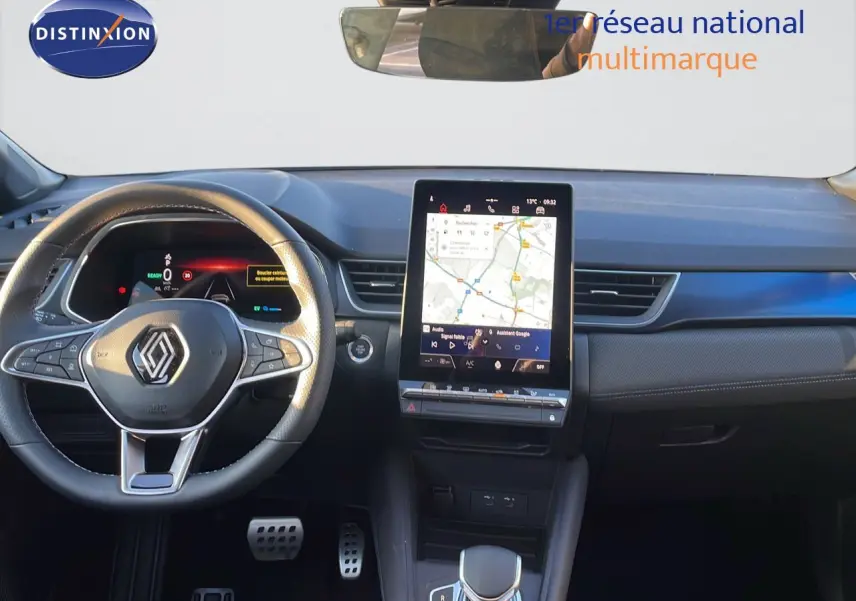 Vue intérieure du tableau de bord Renault Captur E-Tech hybride 2025 avec écran tactile central et volant multifonction noir.