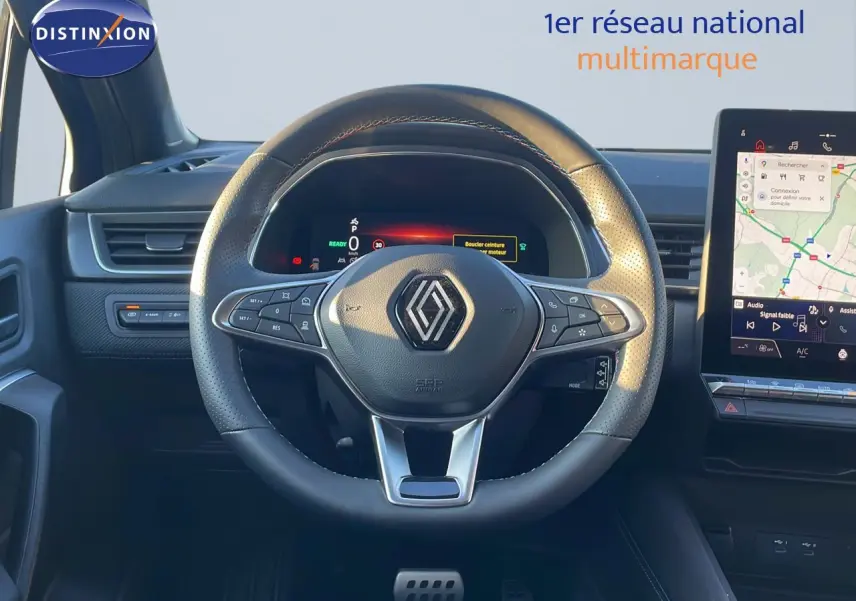 Vue rapprochée du volant en cuir noir du Renault Captur E-Tech Hybrid 2025 avec tableau de bord digital et écran tactile.