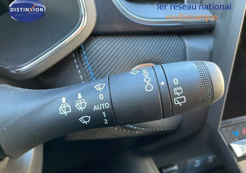 Gros plan sur la commande des essuie-glaces du Renault Captur E-Tech Hybrid 2025 avec surpiqûres bleues sur fond noir.