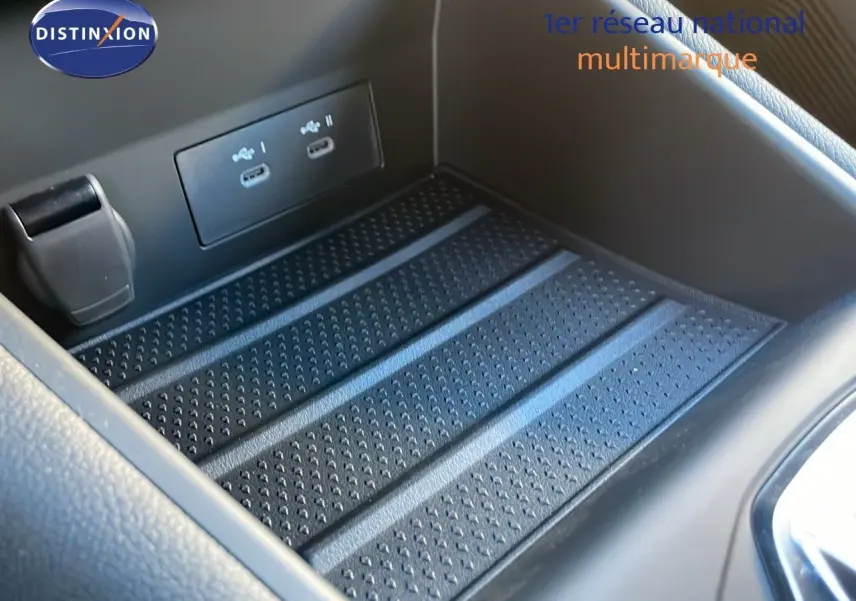 Gros plan sur la console centrale du Renault Captur E-Tech hybride 2025 avec ports USB et surface antidérapante noire.