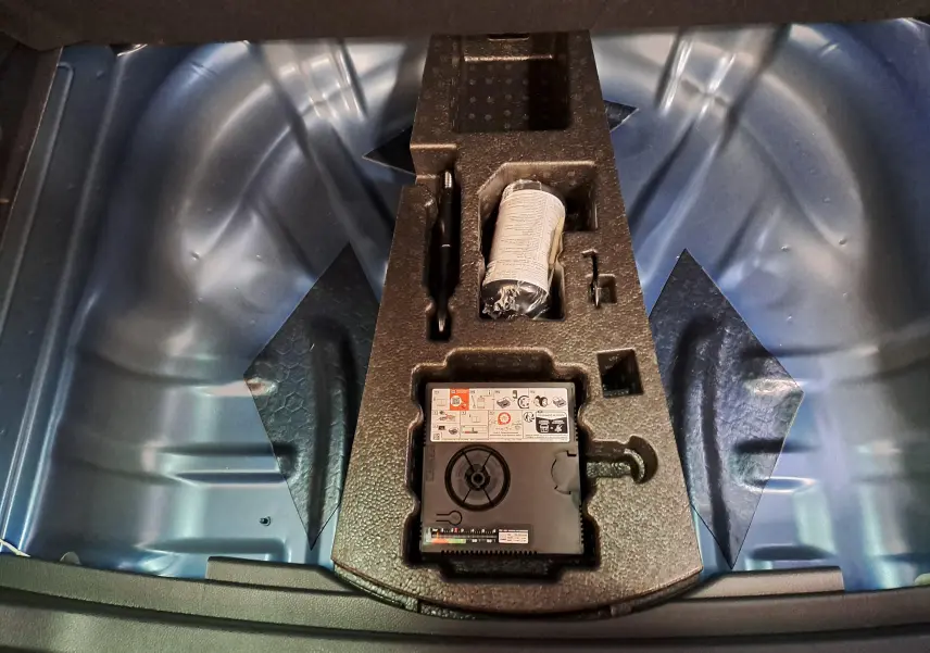 Vue plongeante sur le coffre nu du Skoda Karoq Bleu RS 2025 avec kit de réparation et plancher de chargement variable.