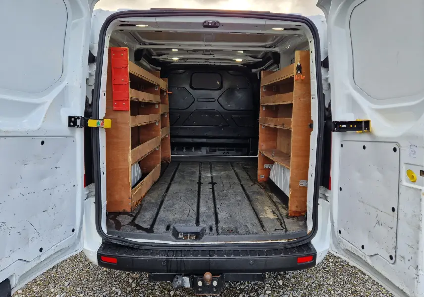 Vue intérieure arrière droite du Ford Transit Custom blanc 2021, montrant des étagères en bois fixées dans le fourgon.