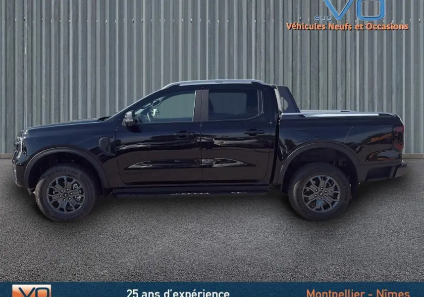 Vue de profil côté gauche du Ford Ranger Wildtrak noir 2025 avec barres de toit, marchepieds et vitres surteintées.