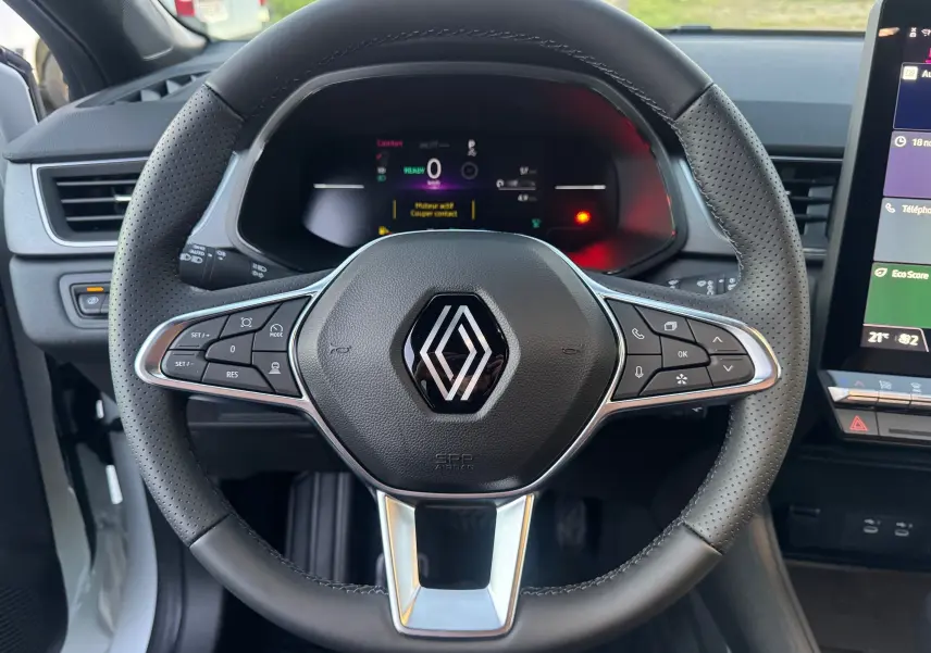 Vue frontale du volant noir perforé du Renault Captur E-Tech Full Hybrid 2025 avec commandes intégrées et tableau de bord numérique.
