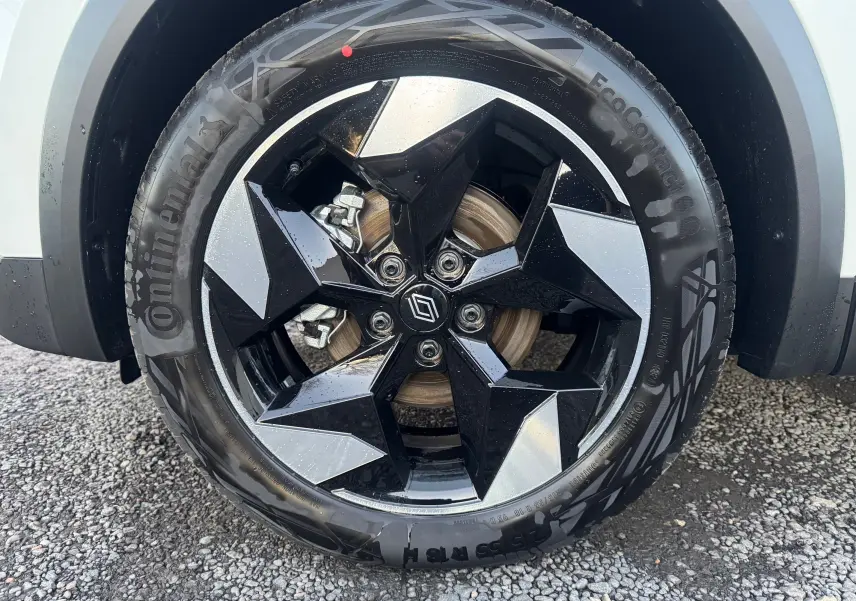 Gros plan sur la roue avant droite du Renault Captur blanc nacré, jante noire et argentée au design géométrique.