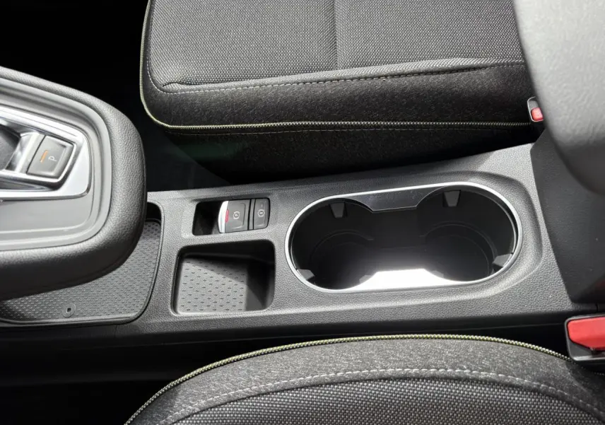 Vue rapprochée de la console centrale noire avec porte-gobelets et bouton frein de parking du Renault Symbioz gris Rafale.