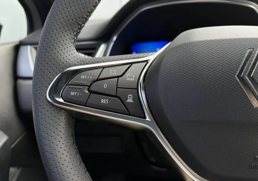 Gros plan sur le côté gauche du volant en cuir perforé du Renault SYMBIOZ gris Rafale avec commandes intégrées.