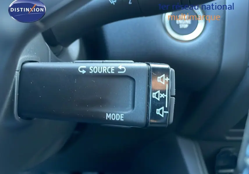 Gros plan sur la commande au volant du Renault Captur blanc nacré, avec bouton source et mode visible, intérieur noir.