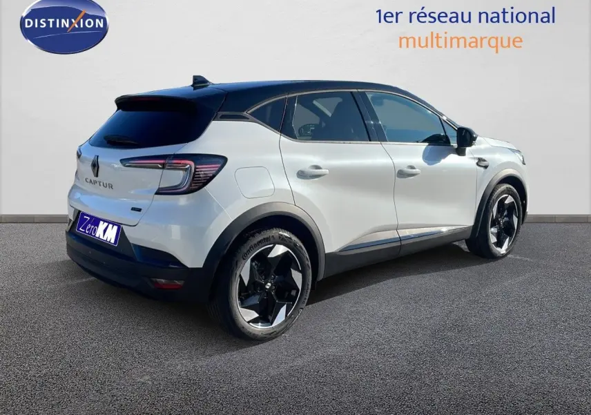 Vue 3/4 arrière droite du Renault Captur blanc nacré avec toit noir, soulignant ses jantes noires et design moderne.