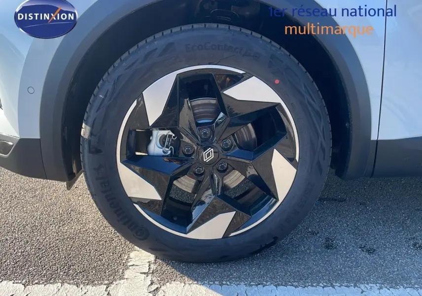 Gros plan sur la roue avant droite du Renault Captur blanc nacré avec jante noire et argentée au design étoilé.