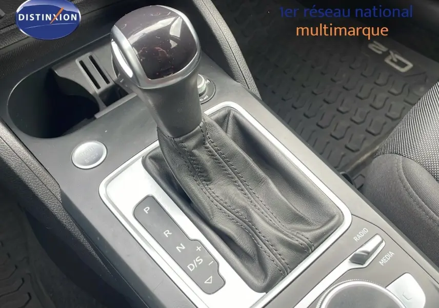 Vue rapprochée du levier de vitesses automatique en cuir noir de l'Audi Q2 35 TFSI S-Line, avec bouton start visible.