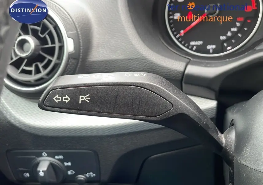 Gros plan sur la commande de clignotants à gauche du volant dans l’habitacle d’un Audi Q2 noir mito metal 2023.