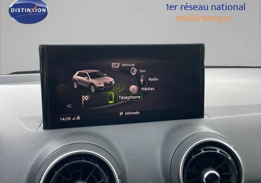 Vue intérieure du tableau de bord de l'Audi Q2 35 TFSI S-Line 2023, écran multimédia et aérateurs ronds gris.